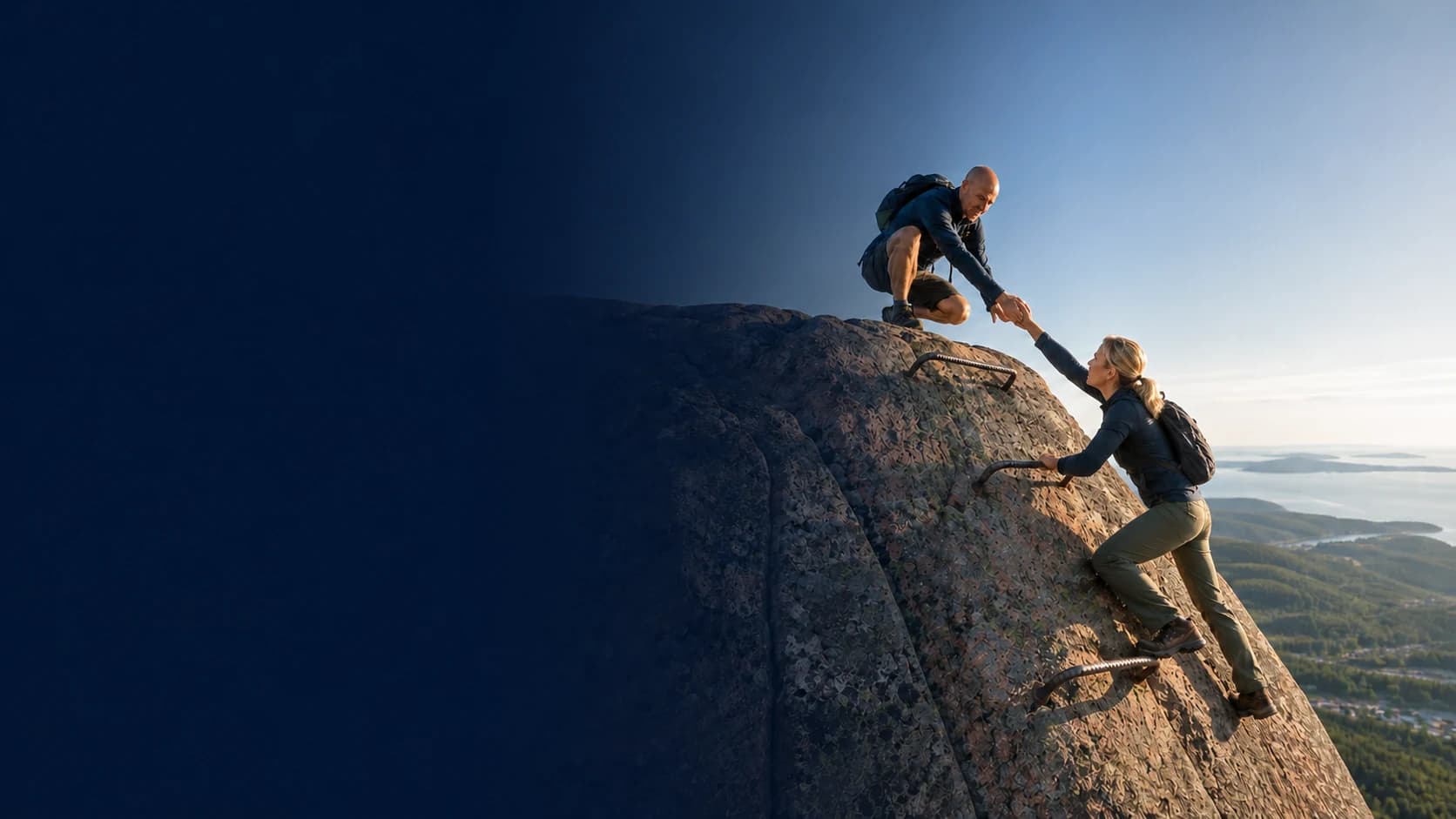 A guide reaches down to help a climber over the final rung on an Acadia mountain trail